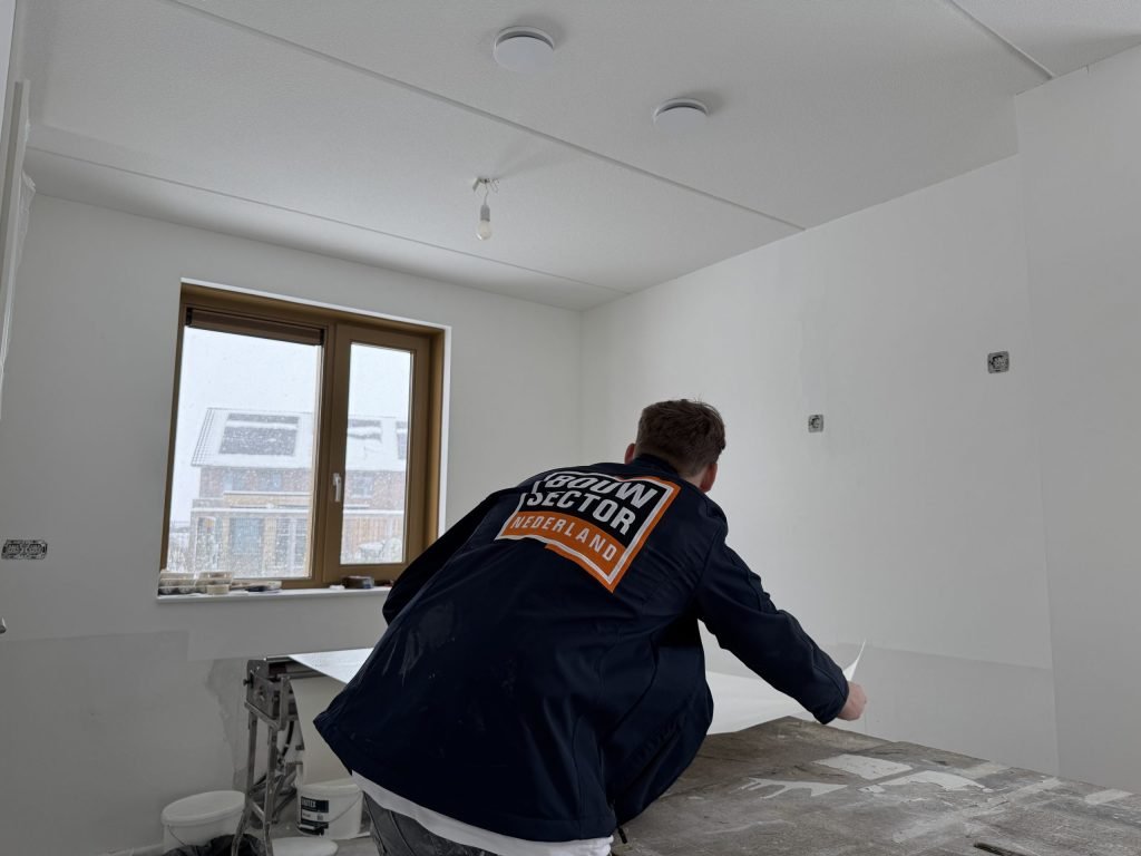Vakman van Bouwsector Nederland buigt zich over de plaktafel in een kale kamer
