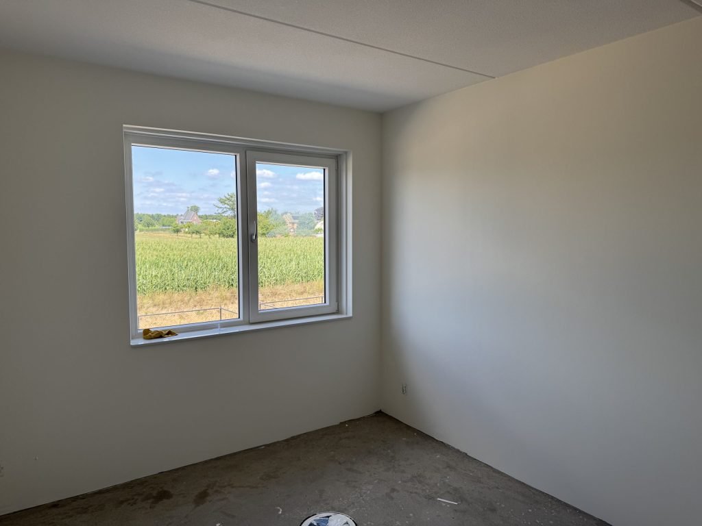 Lichte kamer met gladde wanden en een raam met uitzicht op een akker